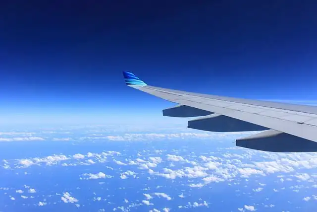 Islamische Bestattungen - Blick aus dem Flugzeugfenster auf den Flügel und einen klaren blauen Himmel mit verstreuten Wolken